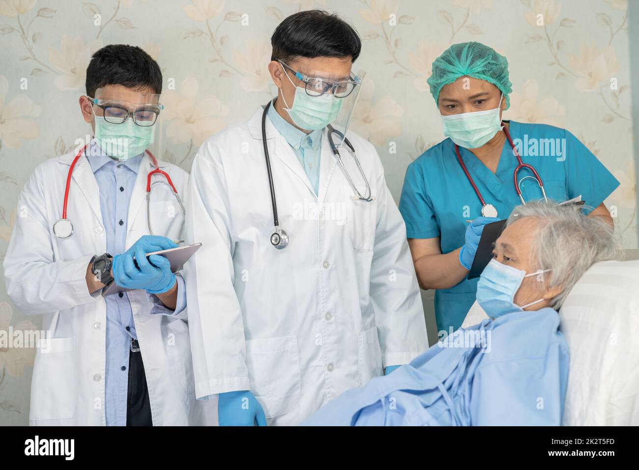 Team medico asiatico controllare la vecchia donna anziana paziente per la malattia alla motivazione nuovo normale per trattare l'infezione Covid-19 Coronavirus al reparto ospedaliero. Foto Stock