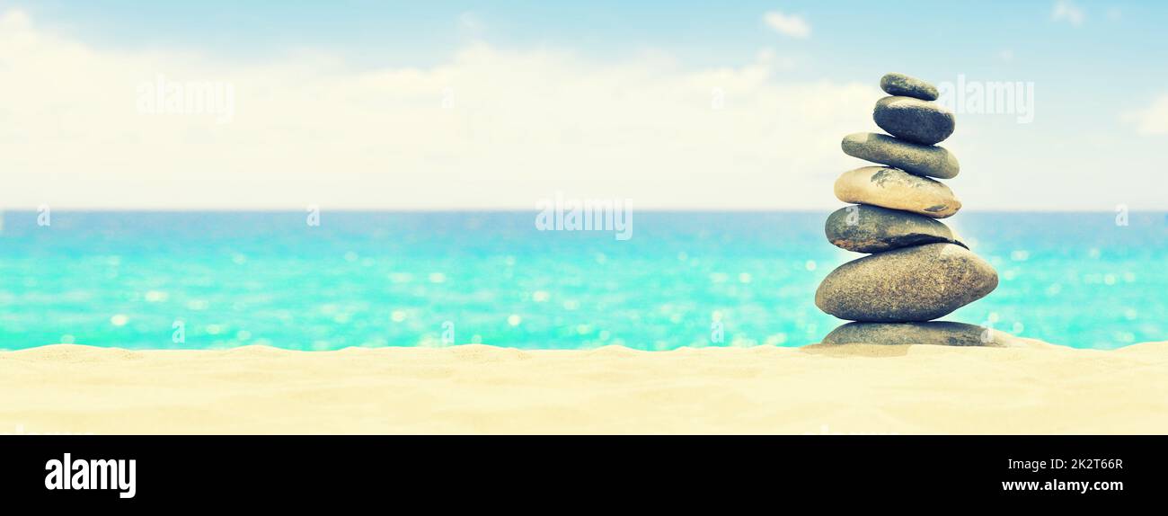 Pietre equilibrato su una spiaggia di ciottoli durante il tramonto. Foto Stock