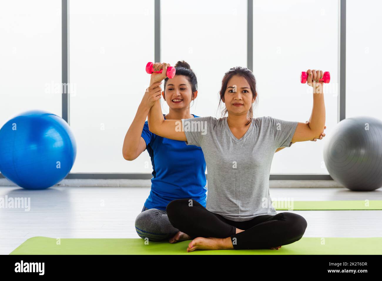 insegnante di donna insegna studente adulto che fa le mani di yoga tenendo manubri Foto Stock