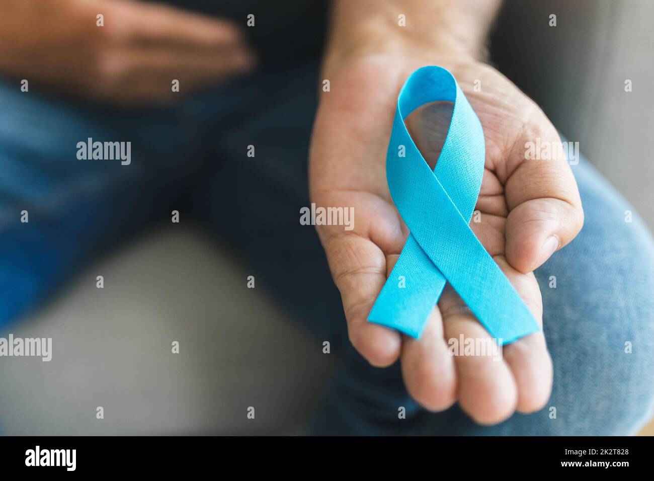 Uomo anziano che tiene un nastro blu di consapevolezza del cancro Foto Stock