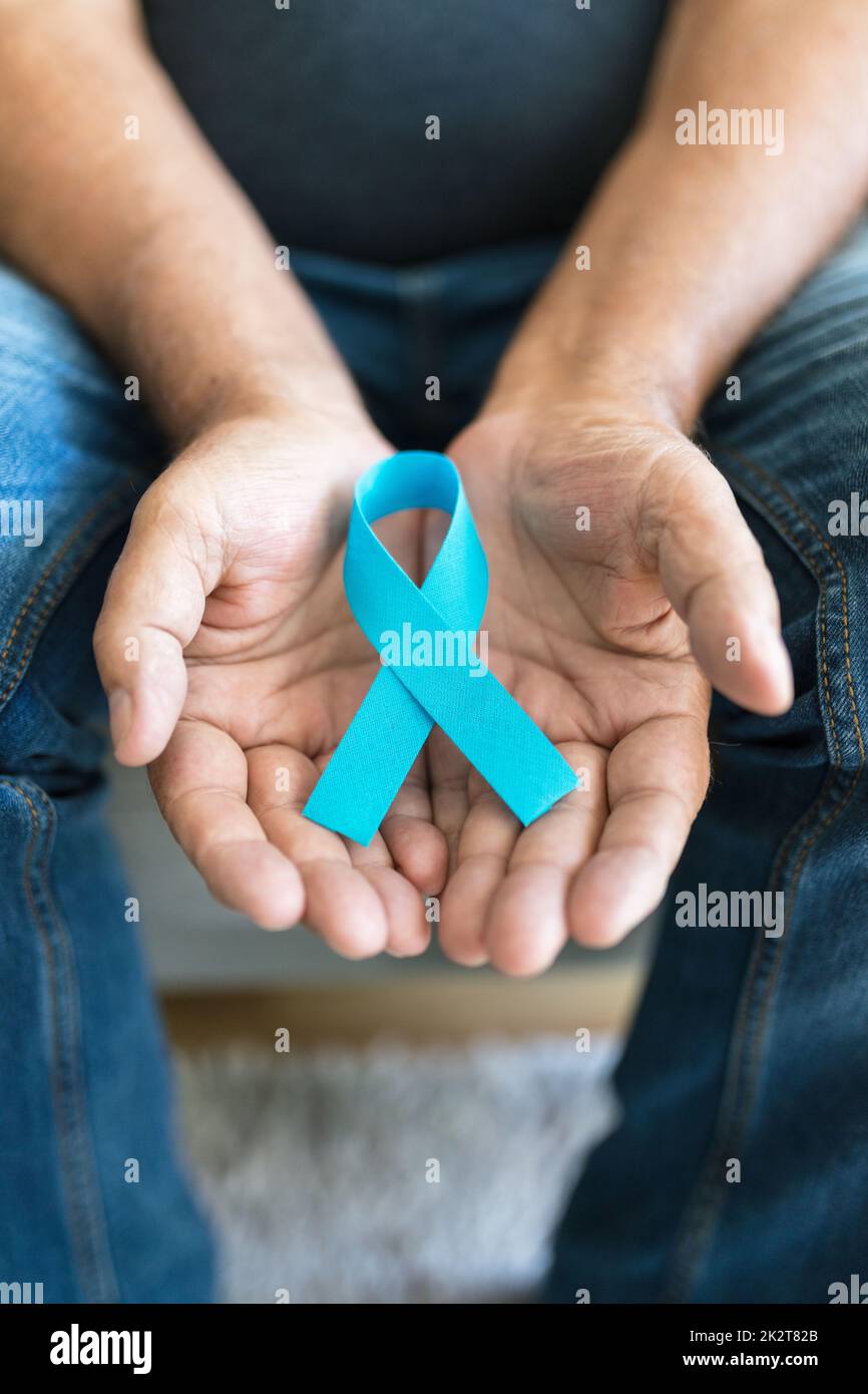 Uomo anziano che tiene un nastro blu di consapevolezza del cancro Foto Stock