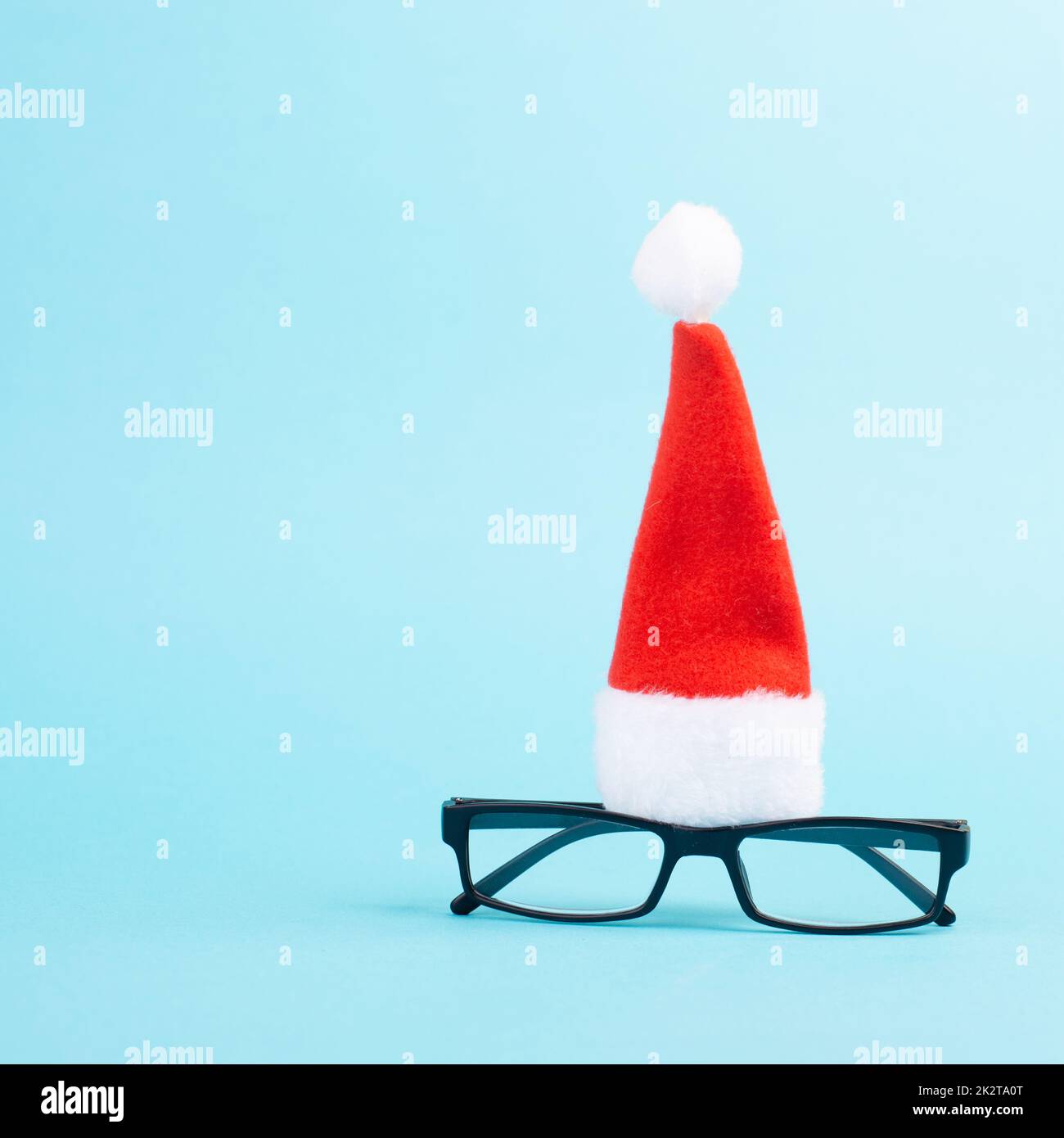 Stagione di Natale, cappello rosso di Babbo Natale e occhiali, faccia divertente, tempo invernale, biglietto di auguri di festa, sfondo blu Foto Stock