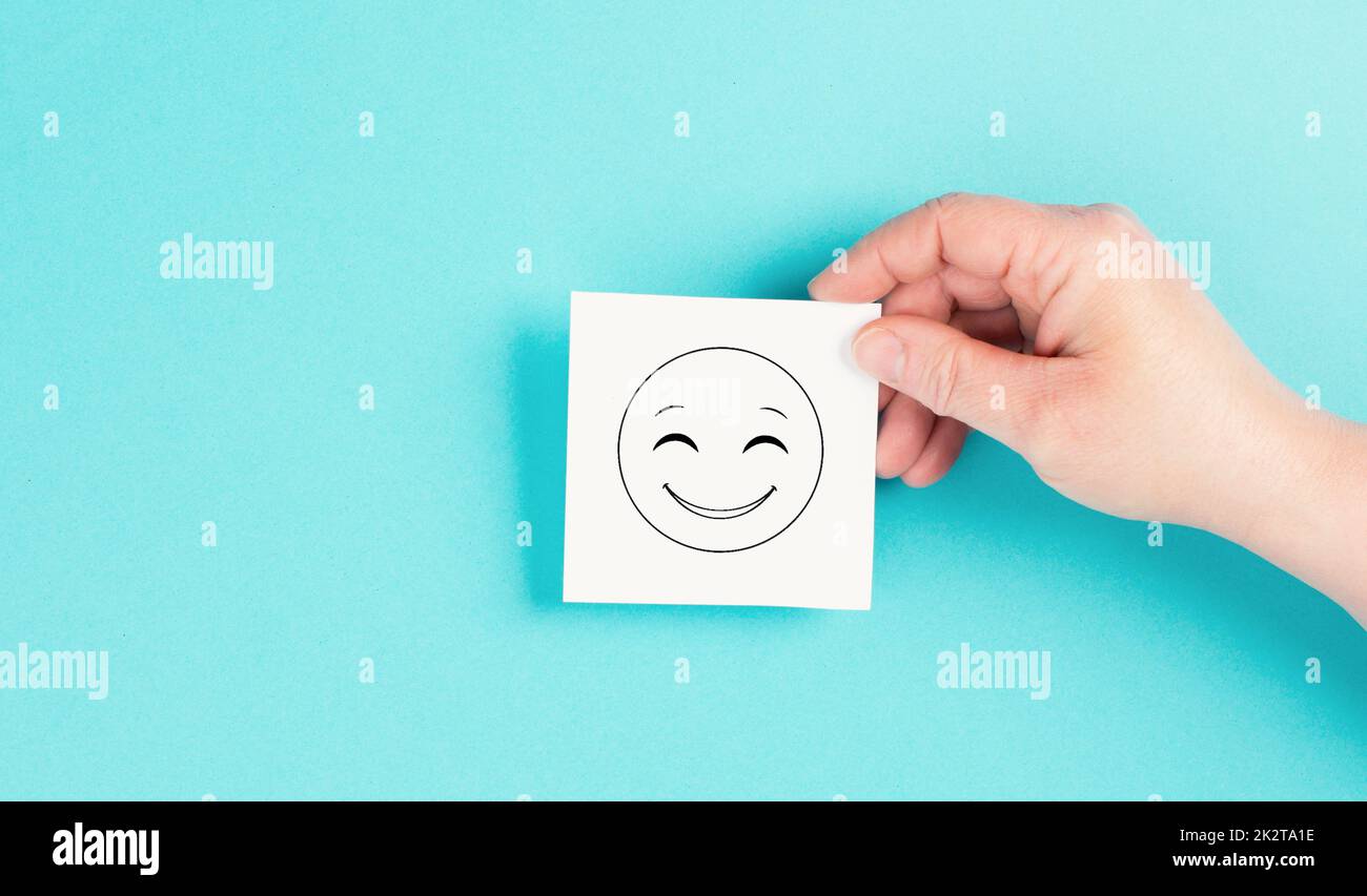 Sorridendo faccia felice su un foglio, emozioni positive, buon feedback dei clienti, ridendo, sfondo blu Foto Stock