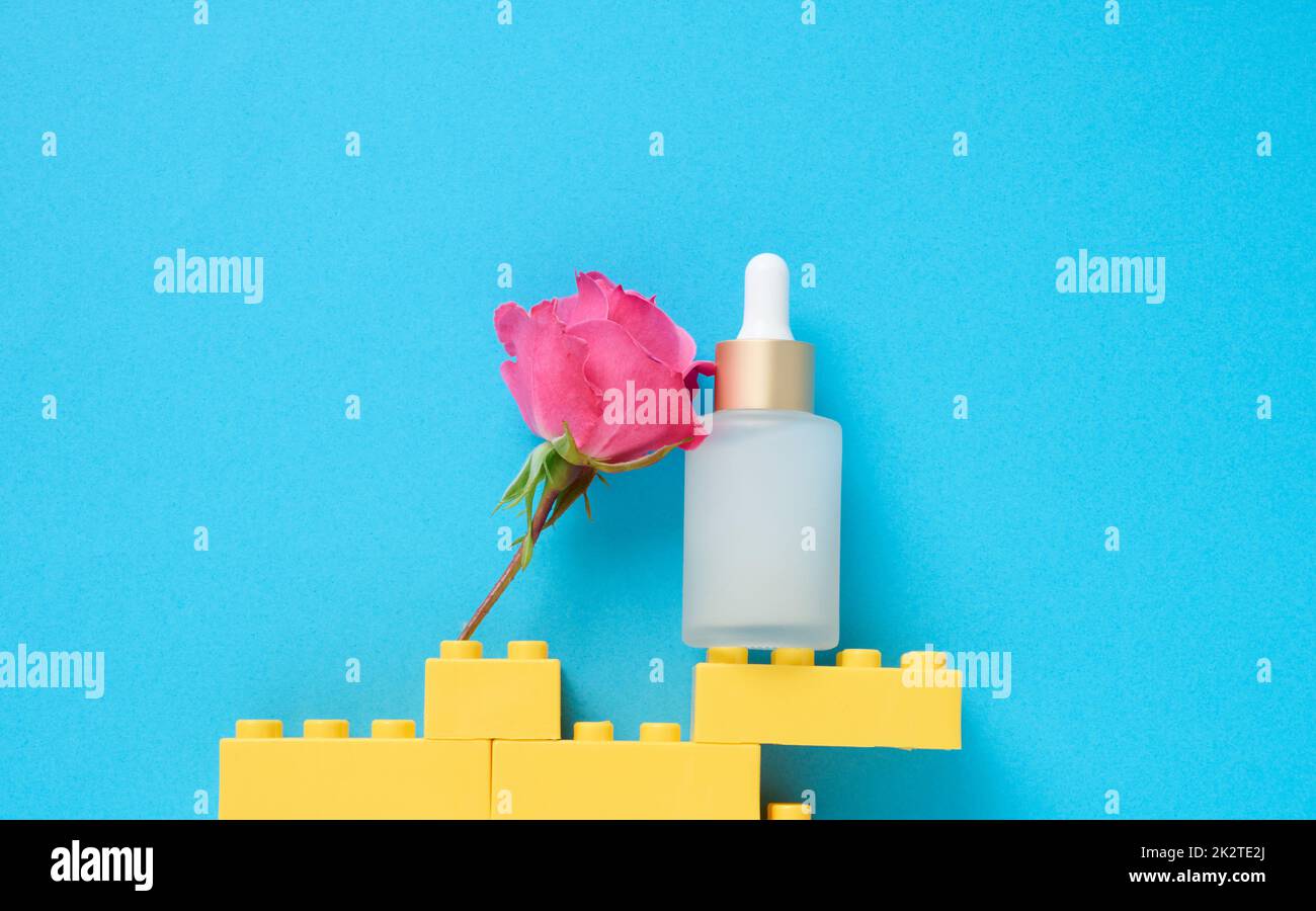 Flacone trasparente in vetro bianco con pipetta per cosmetici, oli, acidi su sfondo blu Foto Stock