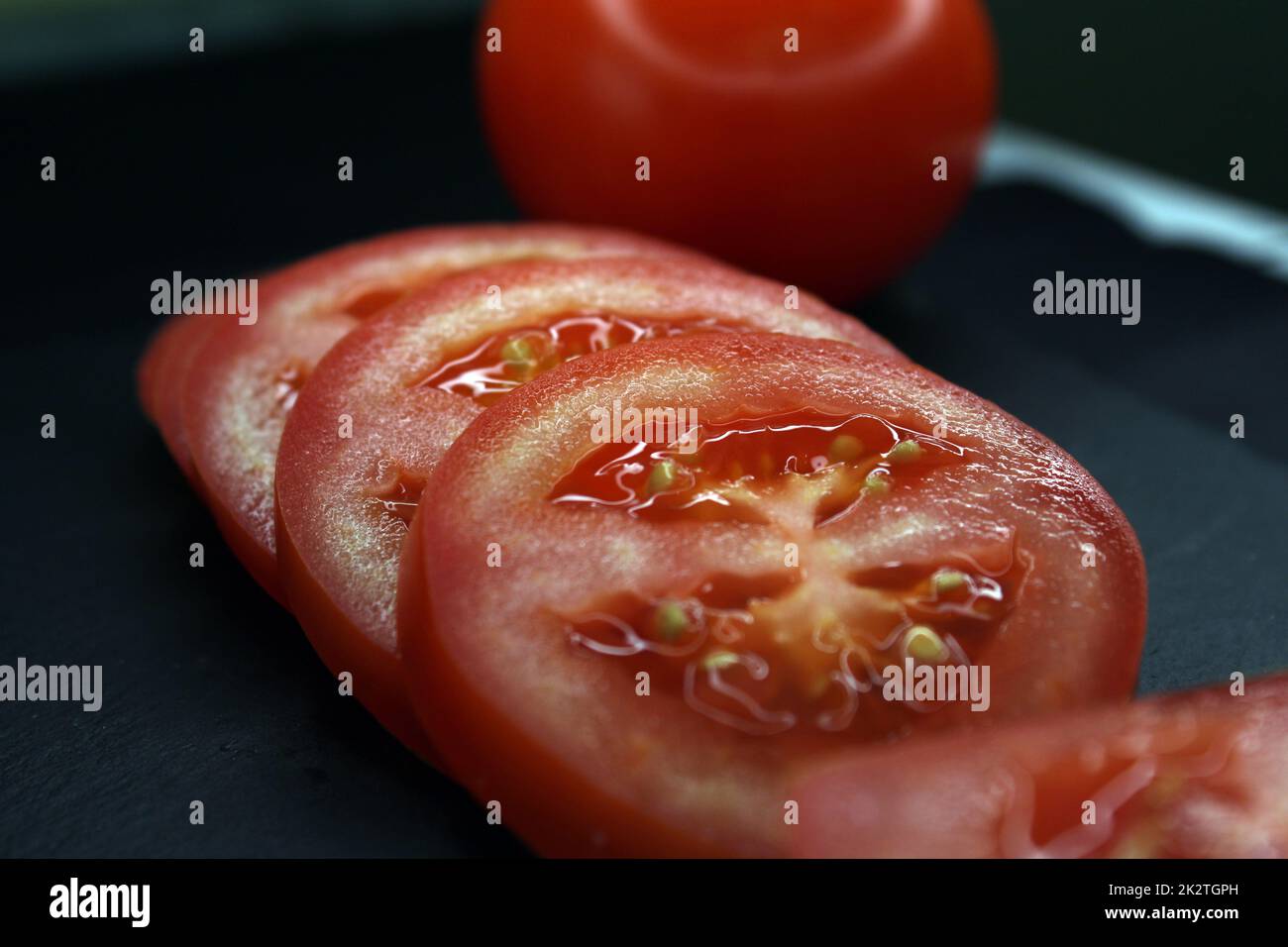 Fette di pomodoro su sfondo nero primo piano. Il concetto di alimentazione sana. Foto Stock