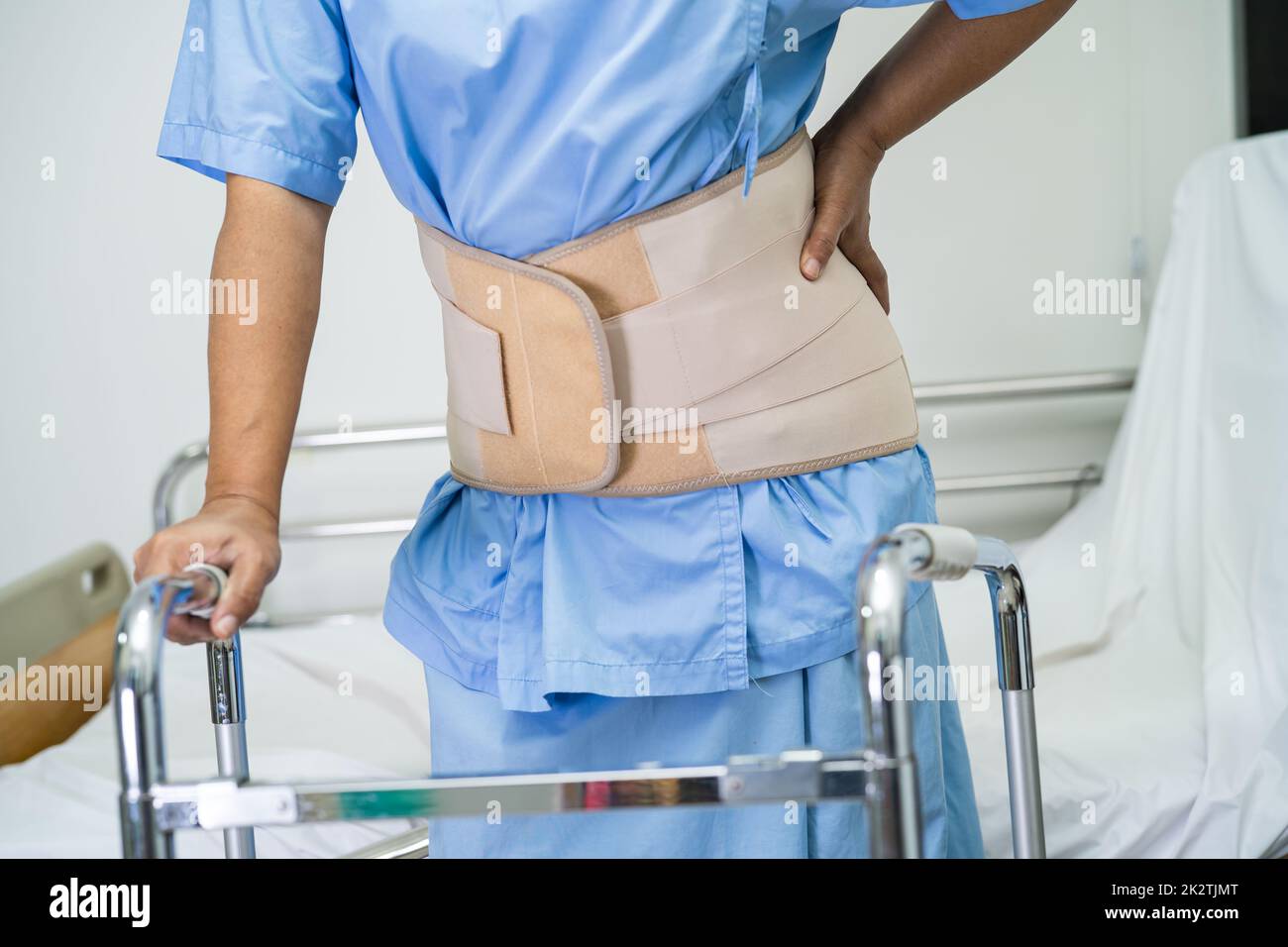 Paziente di signora asiatico che indossa la cintura di sostegno del dolore alla schiena per lombare ortopedico con scuotipaglia. Foto Stock