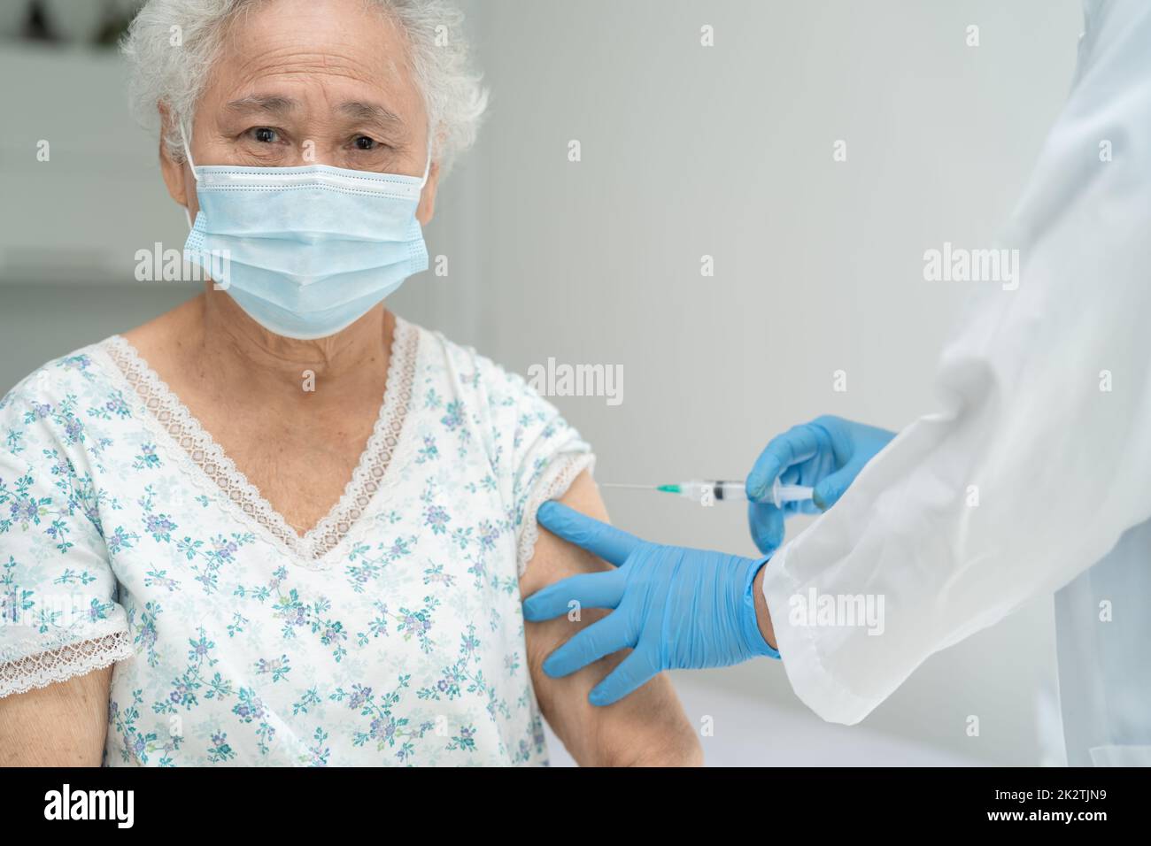 Anziana donna asiatica anziana che indossa la maschera per il viso che riceve covid-19 o il vaccino del coronavirus da parte del medico fare l'iniezione. Foto Stock