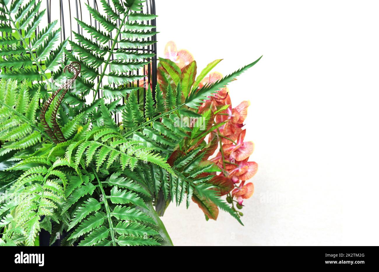 fiore colorato e foglie di palma verde in gabbia decorazione appesa Foto Stock