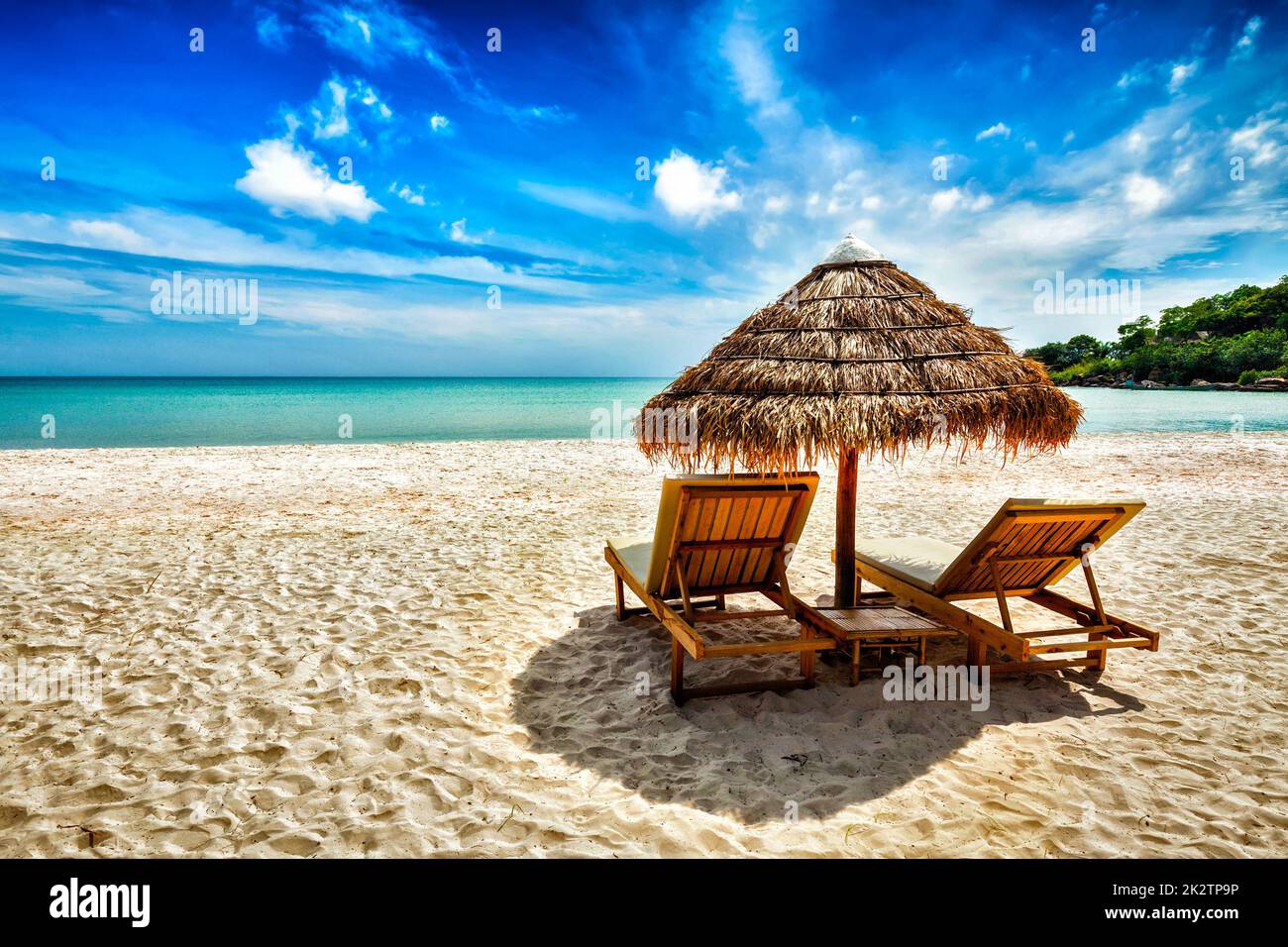 Due sedie a sdraio sotto la tenda sulla spiaggia Foto Stock