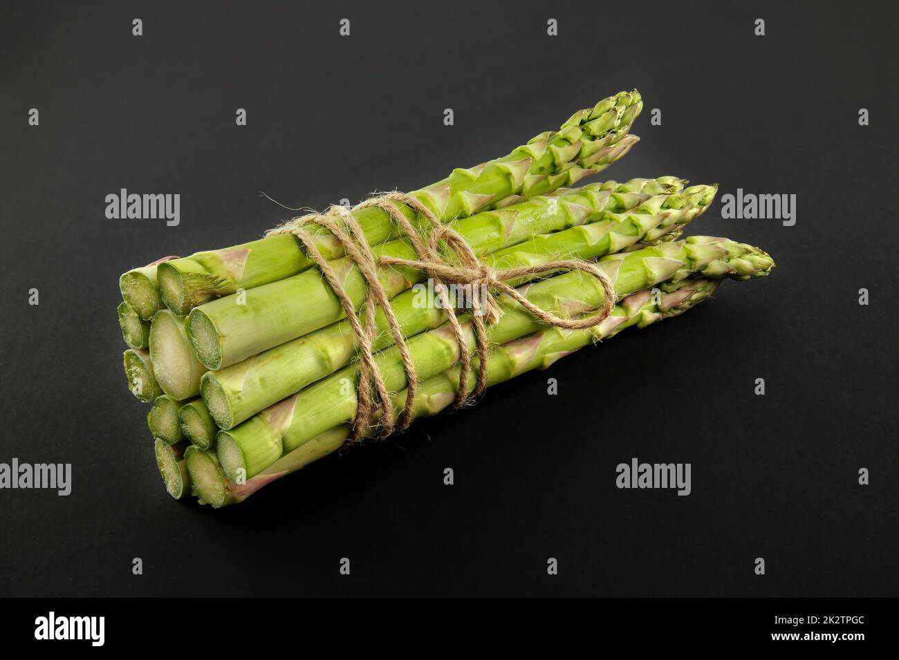 Asparagi verdi legati con corda di iuta su un nero Foto Stock