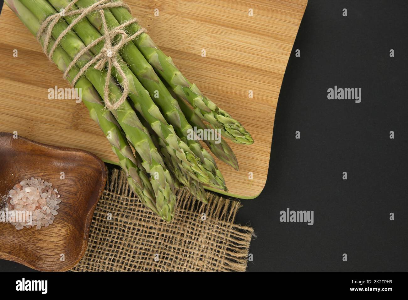 Mazzo di asparagi verdi sul tagliere nero Foto Stock