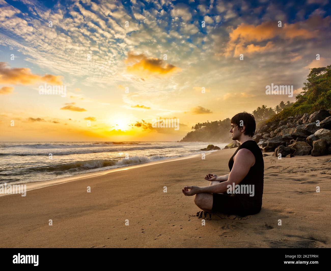 Montare giovane uomo fare yoga meditazione sulla spiaggia tropicale Foto Stock