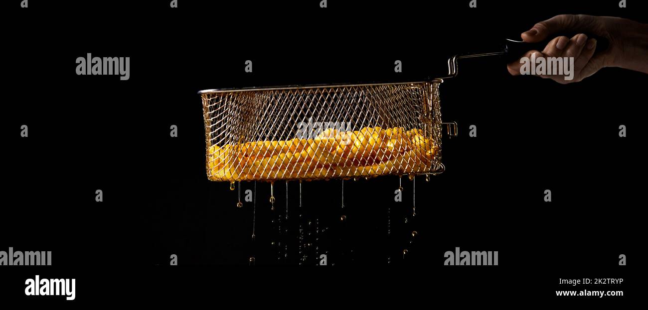 Addetto al raccolto che tiene il setaccio con patatine fritte preparate di recente Foto Stock