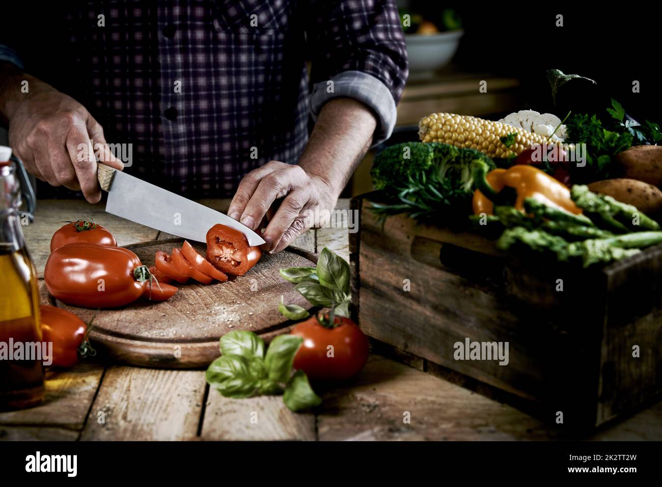 L'uomo del raccolto taglia le verdure fresche durante la preparazione dell'insalata a casa Foto Stock