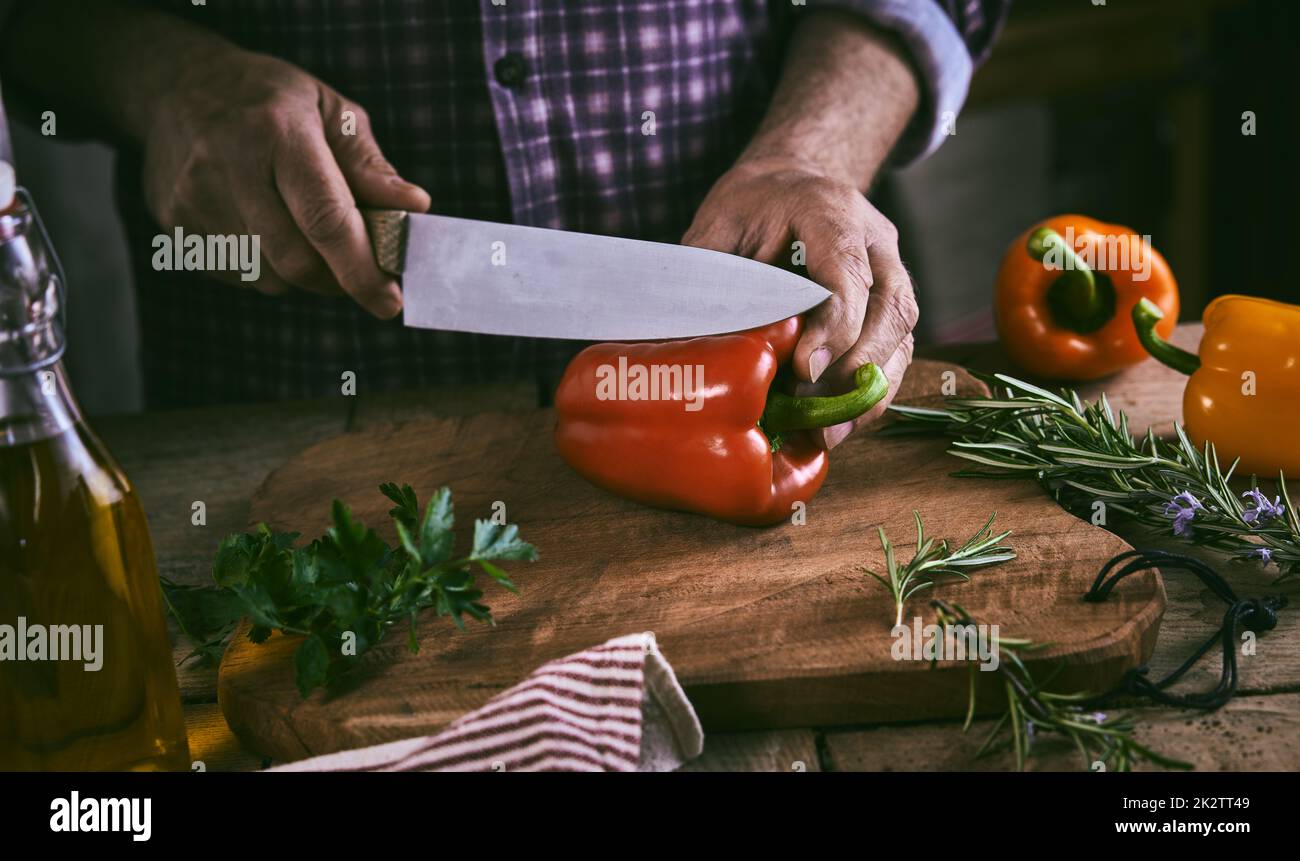 Raccolto cuoco senza volto che taglia il peperone in cucina Foto Stock