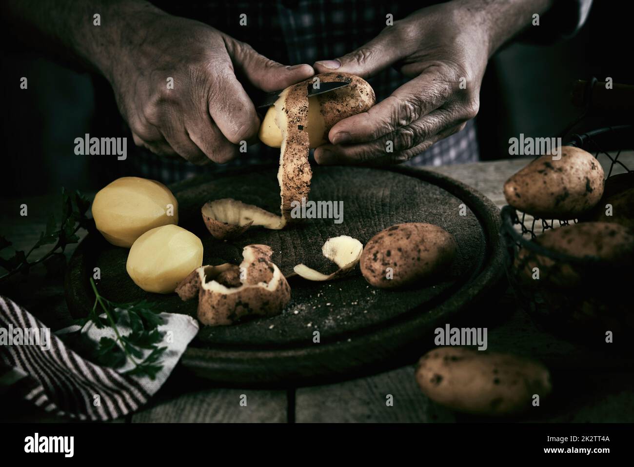 Crop maschio senza volto che sbuccia le patate in cucina Foto Stock