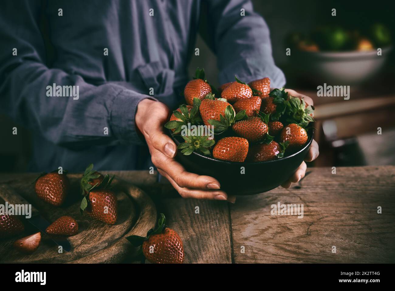 Crop casalinga mettendo ciotola di fragole su tavola Foto Stock