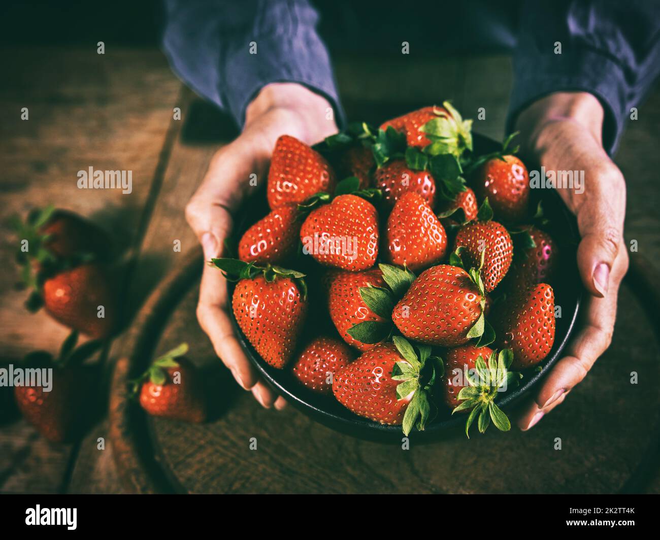 Crop anonimo persona che mostra la ciotola di fragole mature in cucina Foto Stock