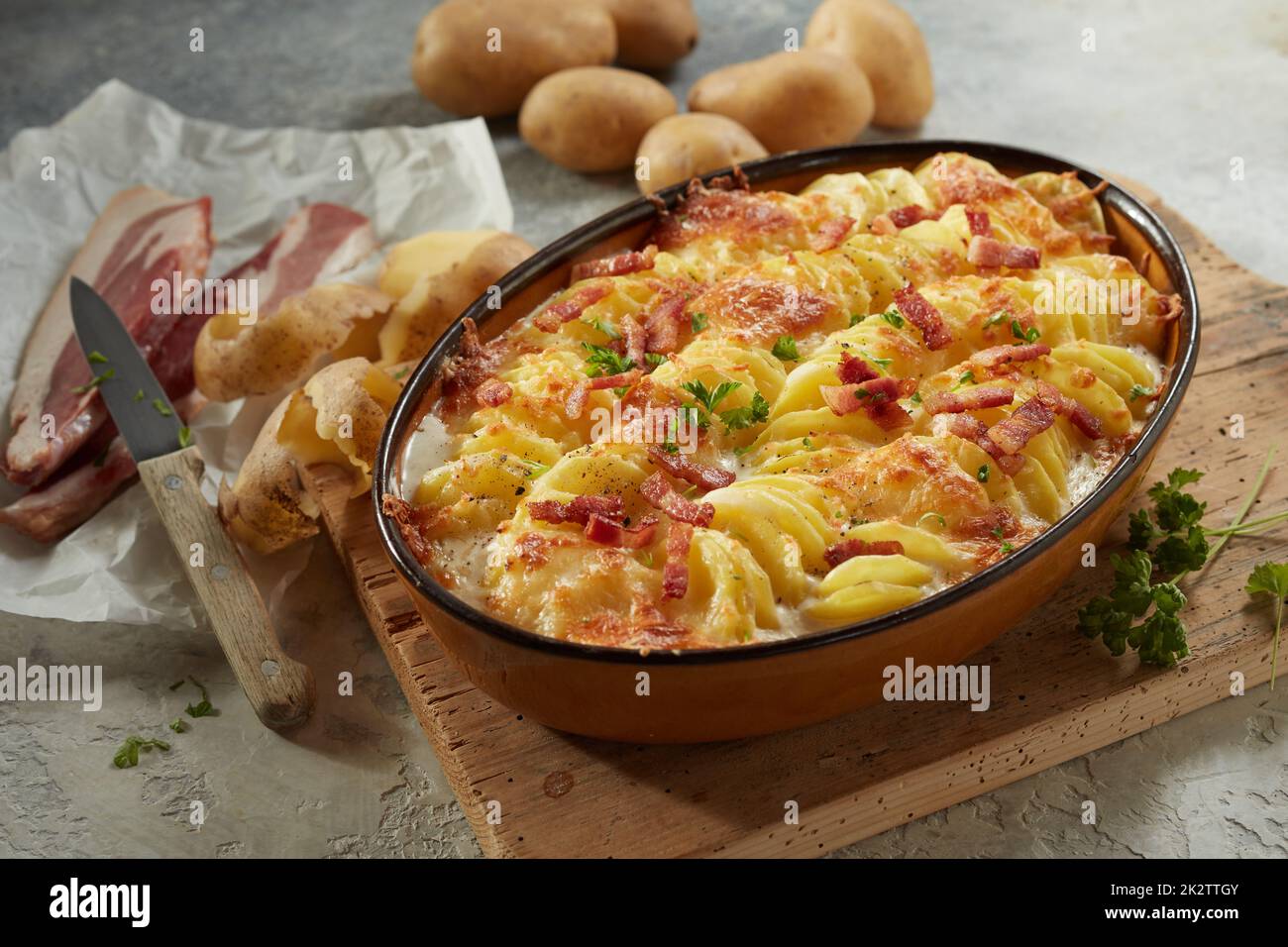 Casseruola con patate e patate servita con fette di pancetta ed erbe aromatiche Foto Stock