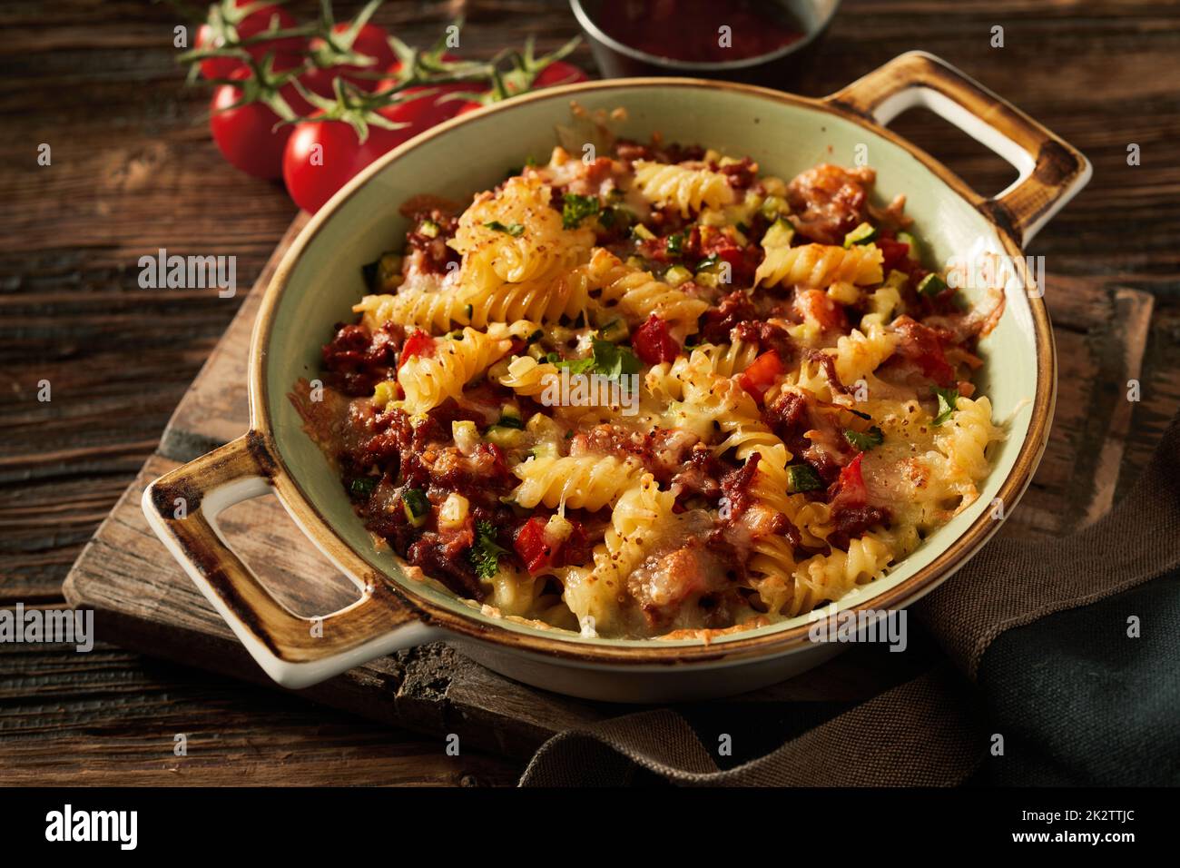 Piatto da forno con deliziosa pasta su asse di legno Foto Stock