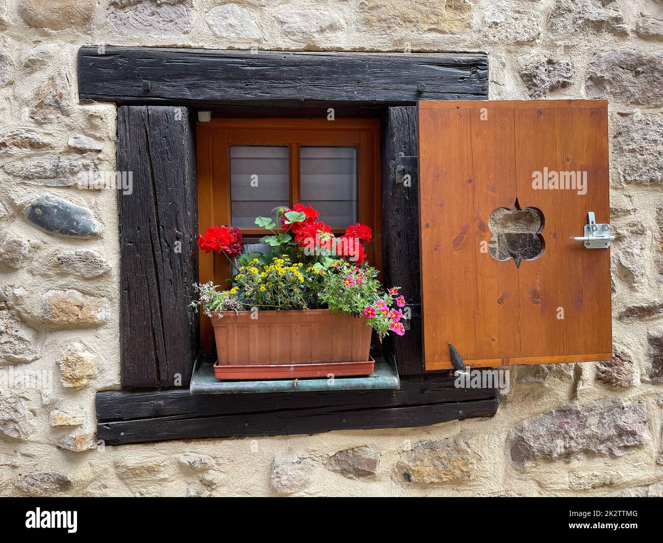 Muro di pietra con fiori in contenitore sul davanzale Foto Stock