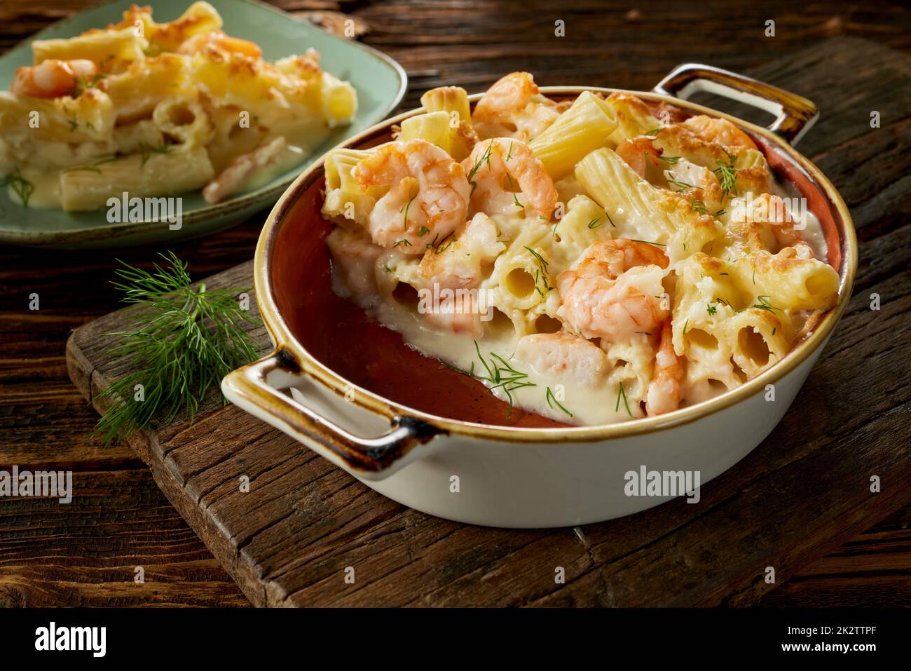 Delizioso piatto con pasta e gamberetti in padella e piatto servito sul tavolo Foto Stock