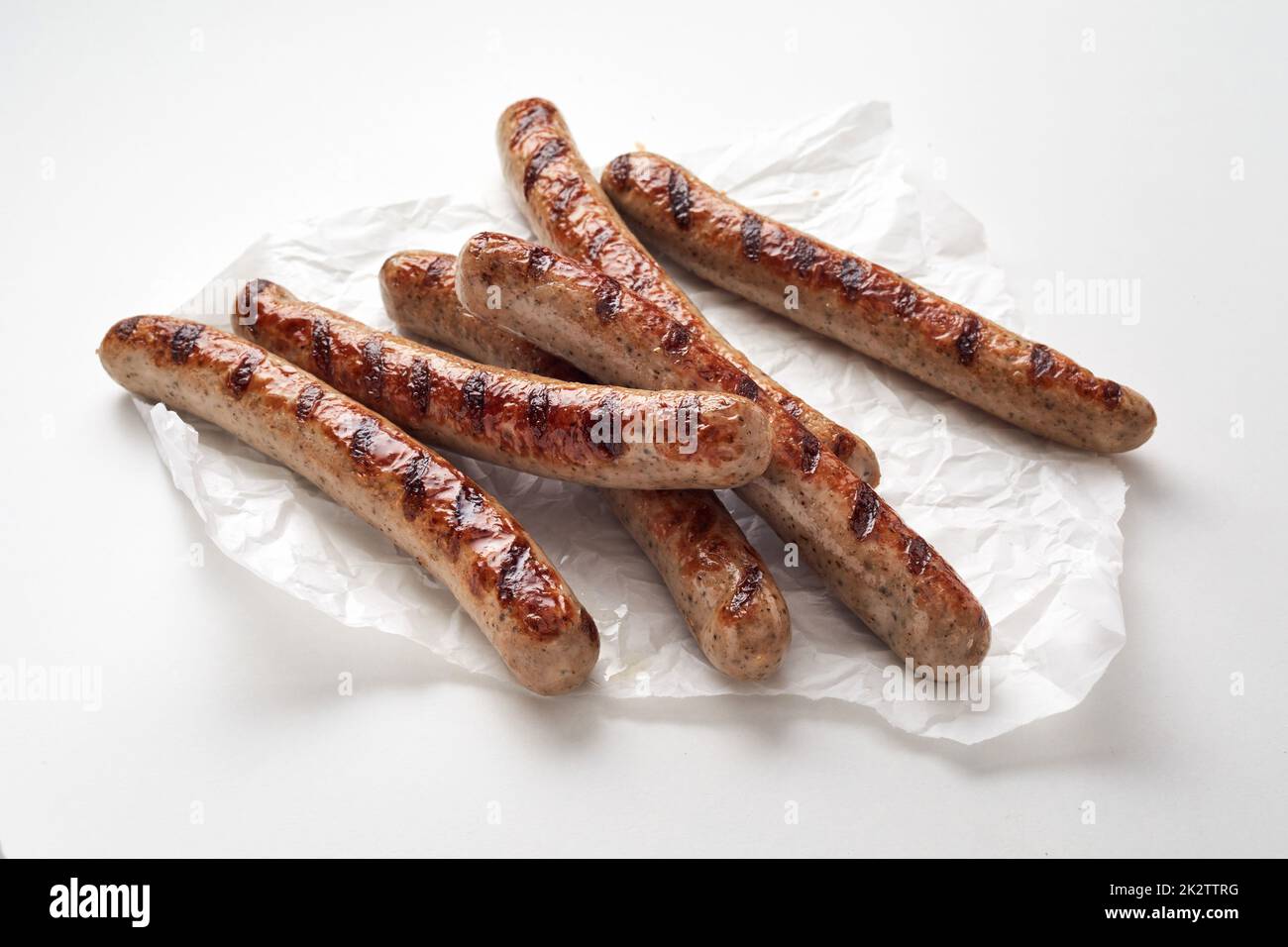 Gustose salsicce arrosto su sfondo bianco Foto Stock