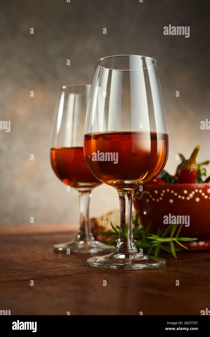 Wineglasses di sherry contro lo sprig del rosmarino sul tavolo Foto Stock