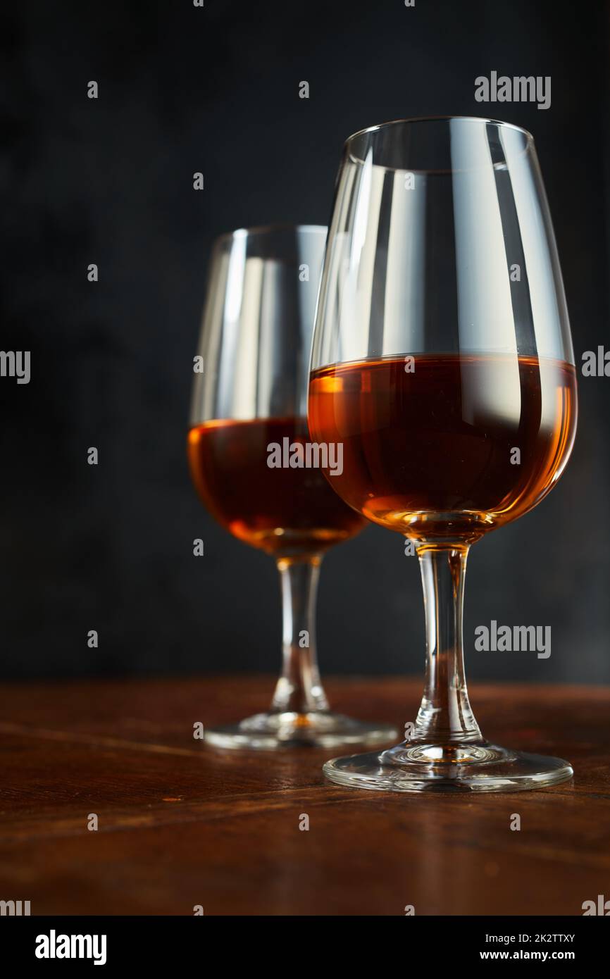 Bicchieri di sherry sul tavolo su sfondo scuro Foto Stock