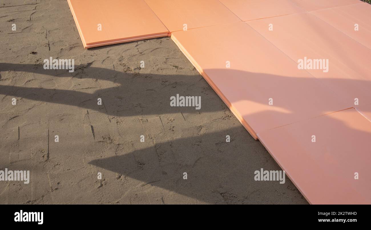 La lastra di polistirene polyplex è posata su sabbia bagnata come isolante per la fondazione di una piscina esterna Foto Stock