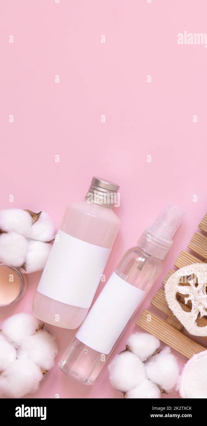 Cosmetici biologici fatti in casa in tubi di plastica e bottiglie e fiori di cotone sul rosa Foto Stock
