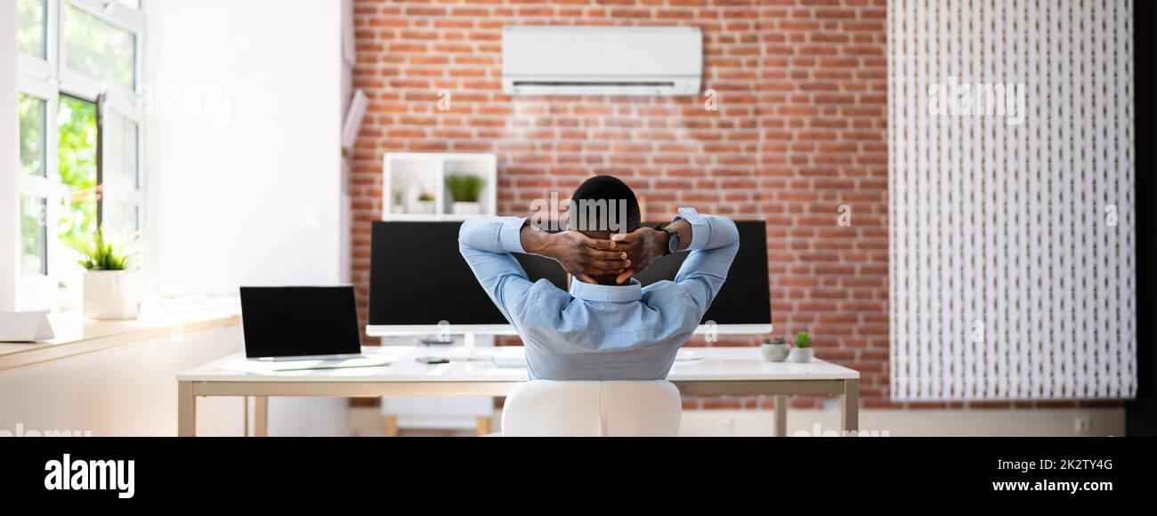 Uomo d'affari che si rilassa in ufficio con aria condizionata Foto Stock