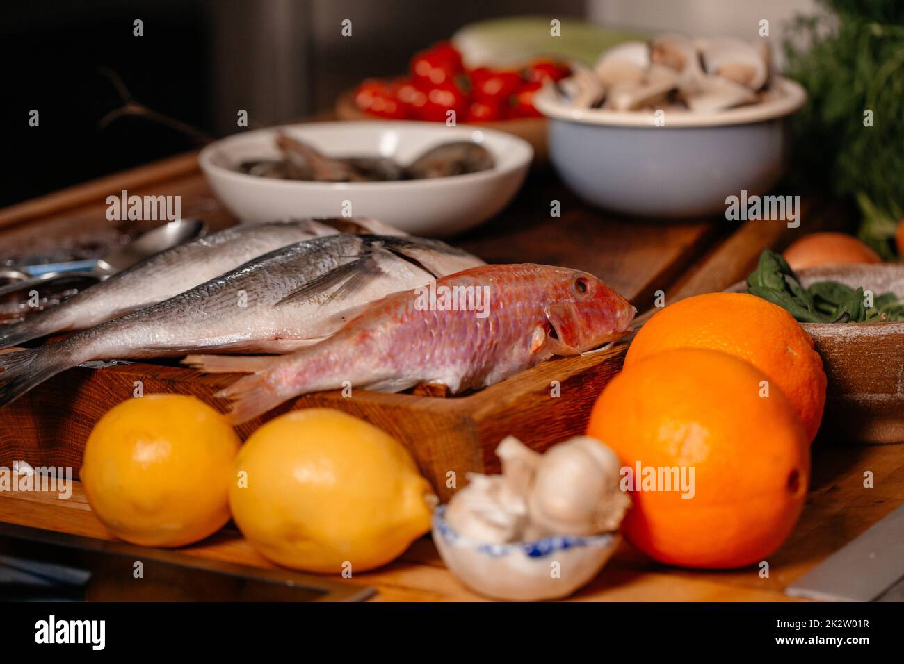 Orate di mare e conchiglie sul tavolo accanto a verdure e frutta. Ingredienti per preparare una deliziosa zuppa. Cucina raffinata. Foto Stock