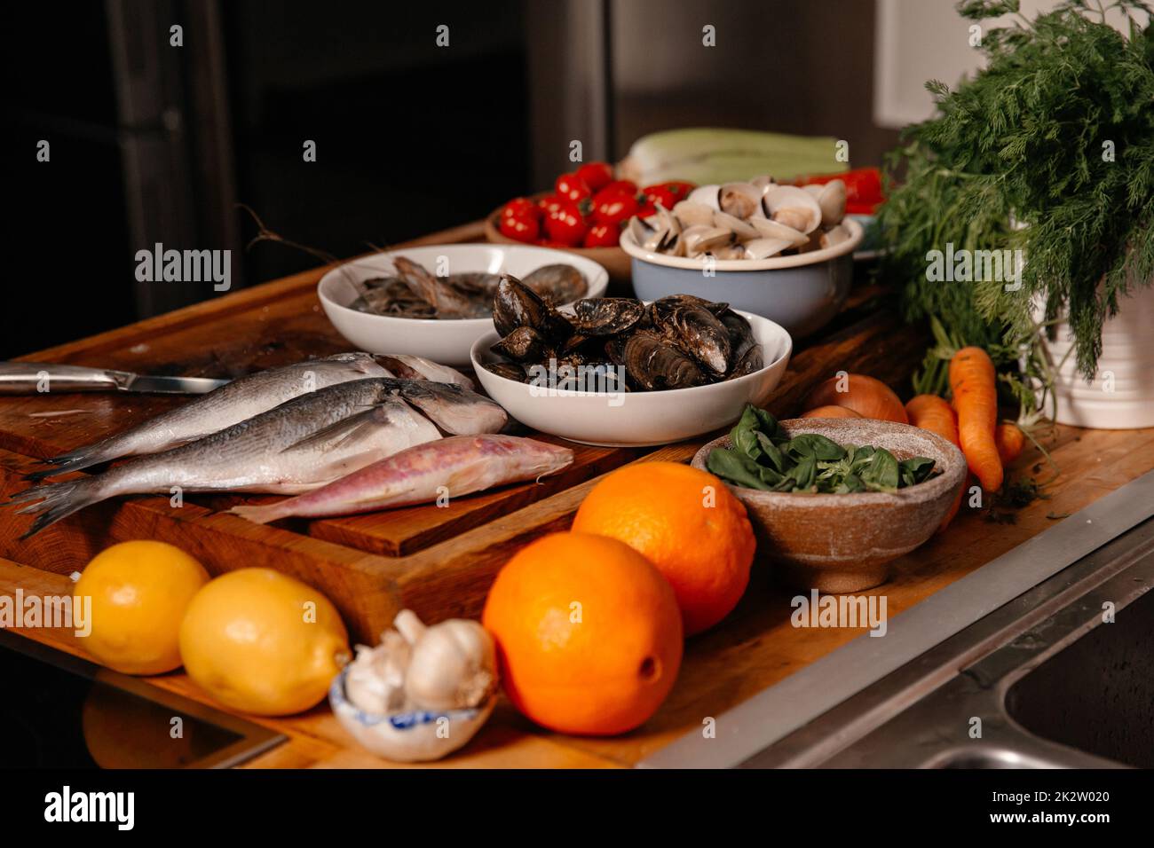 Orate di mare e conchiglie sul tavolo accanto a verdure e frutta. Ingredienti per preparare una deliziosa zuppa. Foto Stock