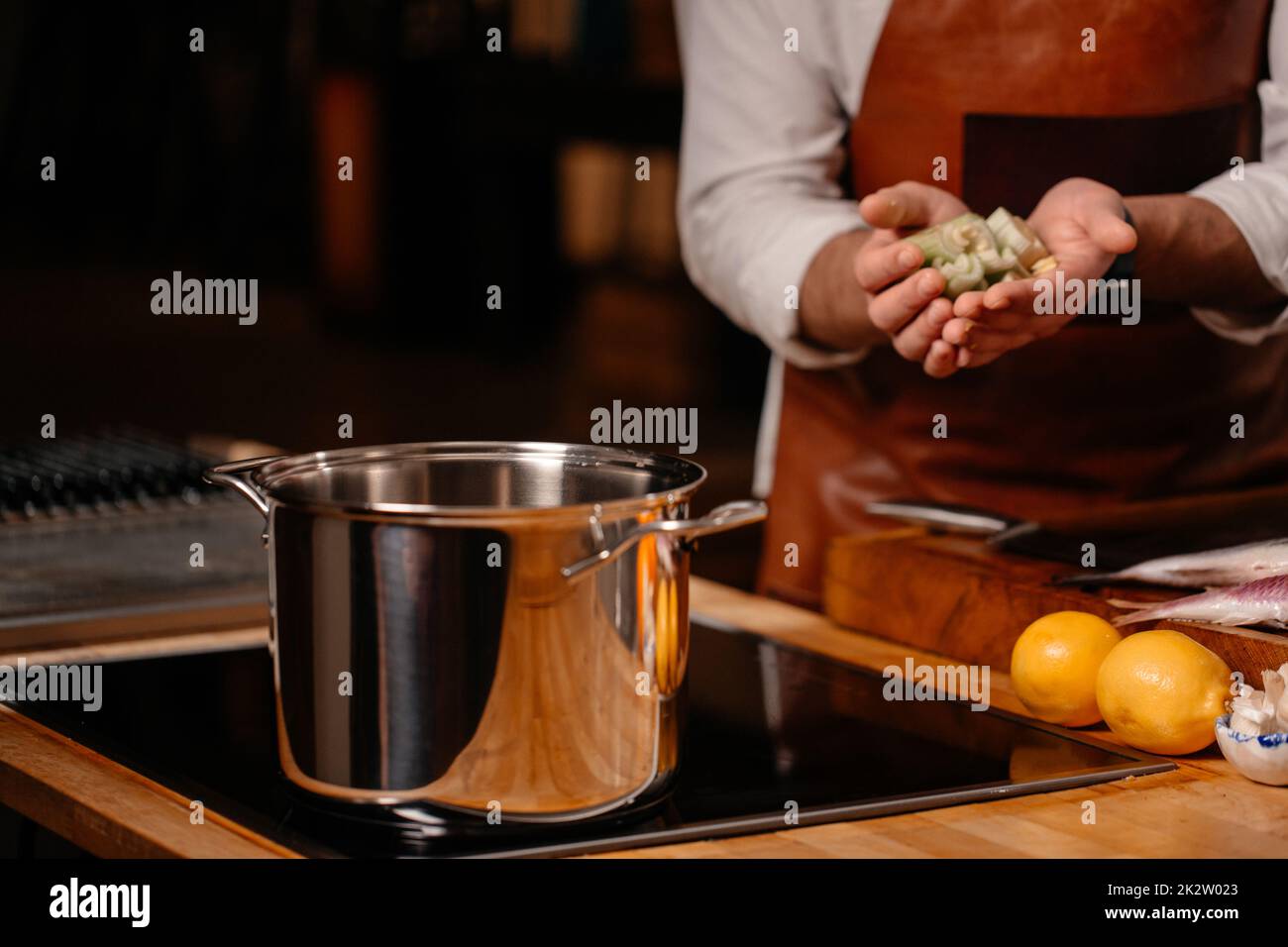 Cuocete gli ingredienti in una pentola grande in una cucina con una serie di attrezzature ed elettrodomestici sullo sfondo. Foto Stock