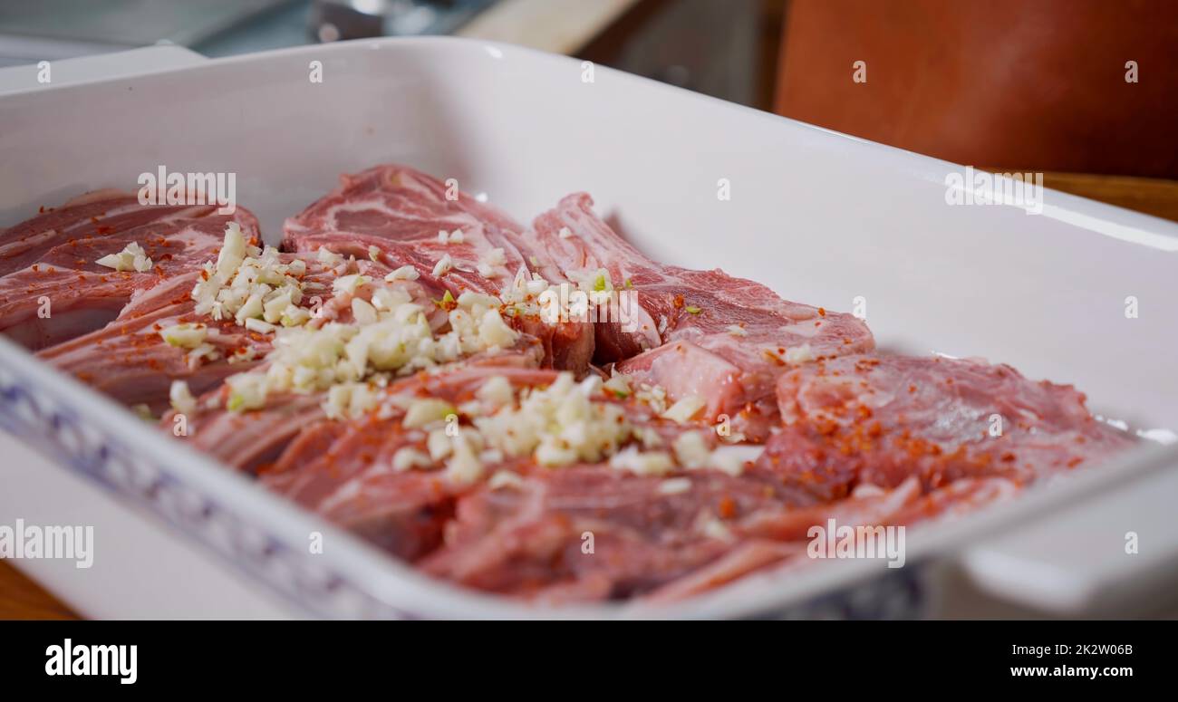 Carne di agnello condita con pepe, aglio, sale prima della cottura. Agnello crudo succoso. Foto Stock