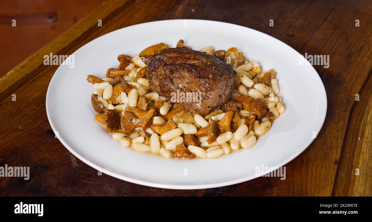 Chef professionista che cucinano in cucina. Piatto gustoso con bistecca di manzo e fagioli. Foto Stock