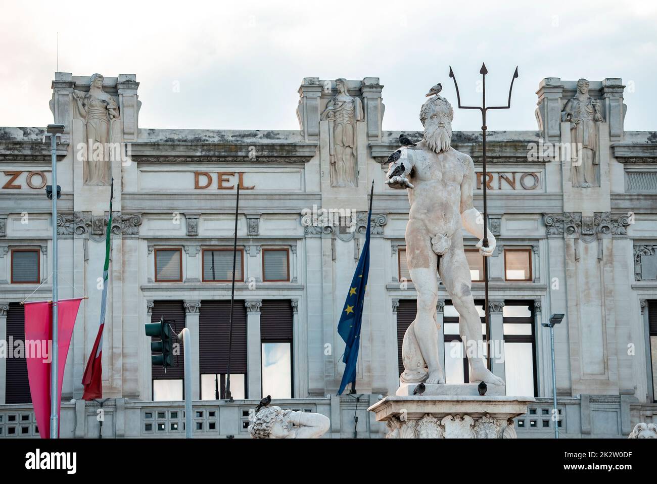 Uccelli appollaiati sulla fontana della Statua del Nettuno con edificio storico sullo sfondo Foto Stock
