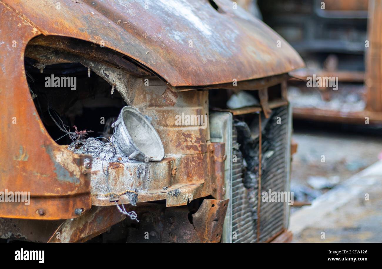 L'auto è stata completamente distrutta da un incendio. Auto abbandonata, bruciata e arrugginita sulla strada. Nel parcheggio c'erano delle auto in fiamme. Guerra della Russia contro l'Ucraina. Buchi di proiettile e shrapnel in automobili. Foto Stock