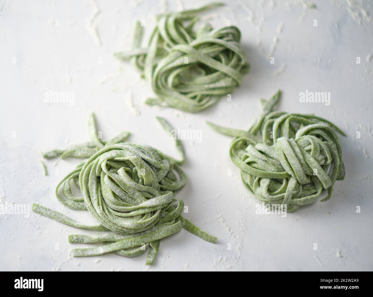 Spinaci crudi fatti in casa. Fettuccine pasta cruda. Nido di tagliatelle verdi. Foto Stock