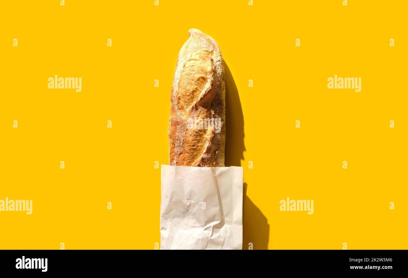 Baguette appena sfornata su sfondo giallo in carta artigianale. Foto Stock