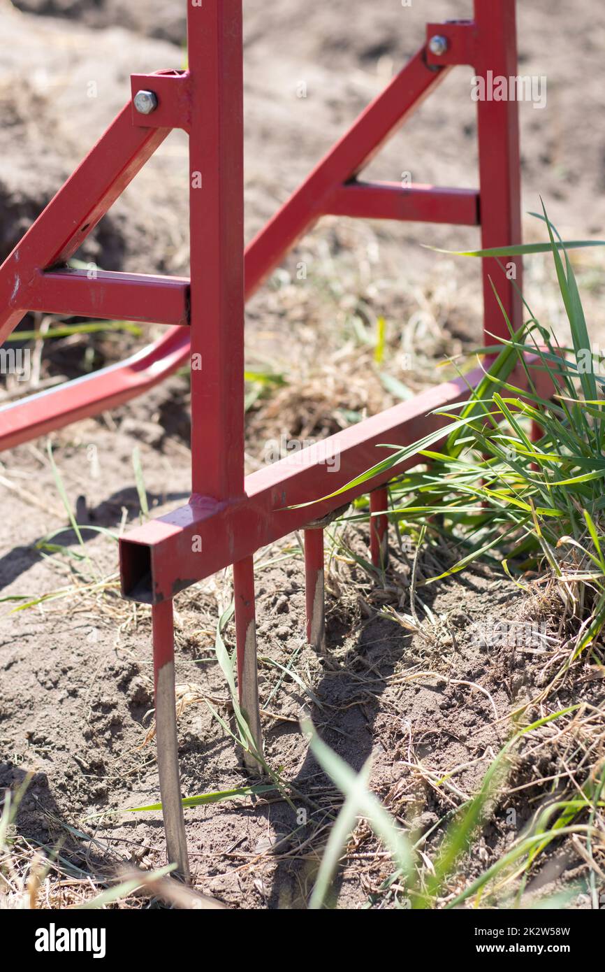Pala rossa a forma di forchetta in giardino. Pala miracolosa, strumento pratico. Coltivatore manuale. Il coltivatore è uno strumento efficace per il dissodamento. Allentamento del letto. Strumenti agricoli sostenibili. Foto Stock