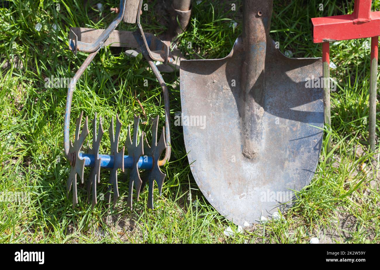 Attrezzi di giardinaggio. Attrezzi da giardino sullo sfondo di un giardino in erba verde. Attrezzatura estiva. Pala, forchetta e lievito in polvere impilati nel giardino all'esterno. Il concetto di attrezzi di giardinaggio. Foto Stock