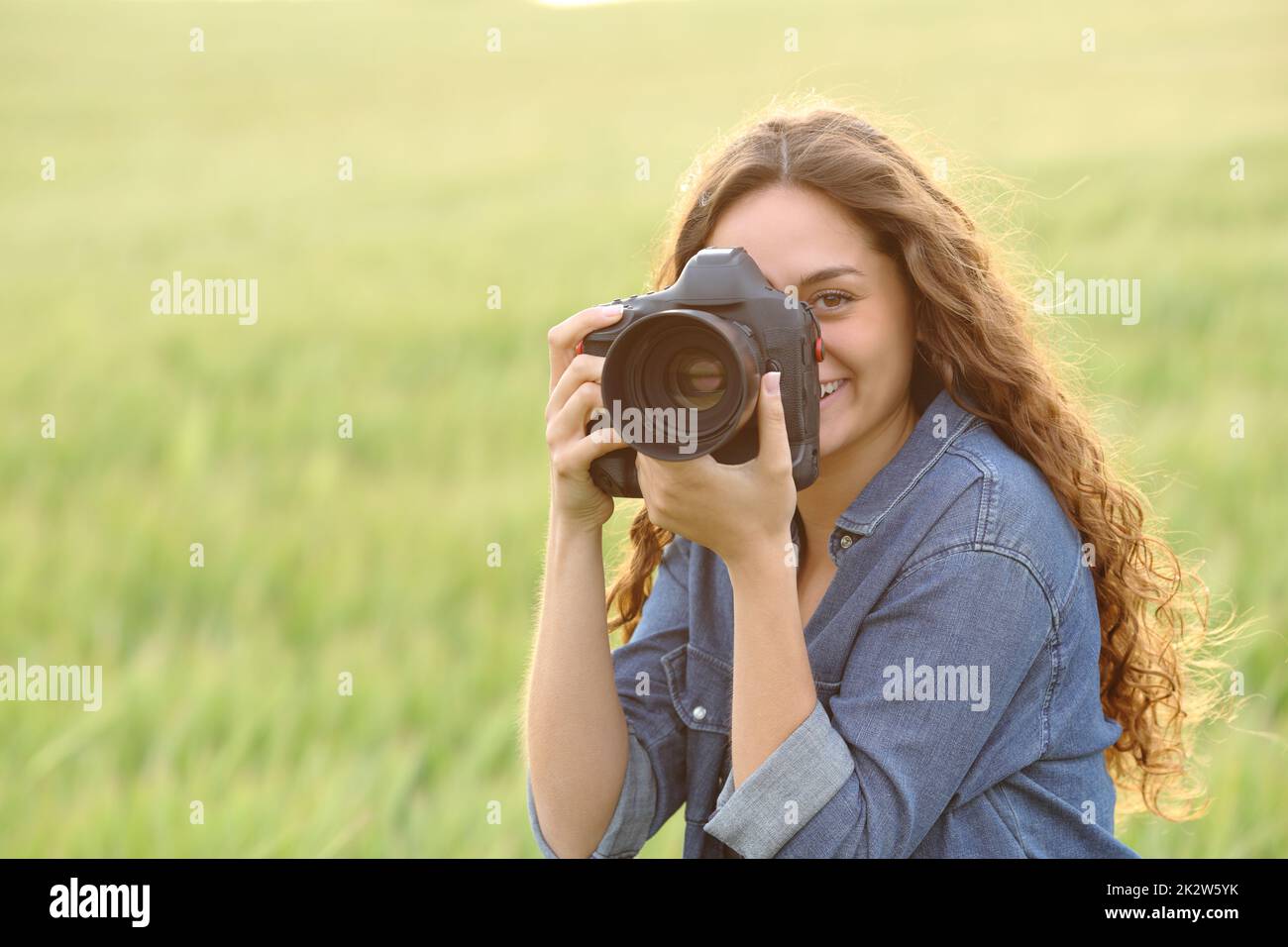 Donna che scatta foto in un campo di grano Foto Stock