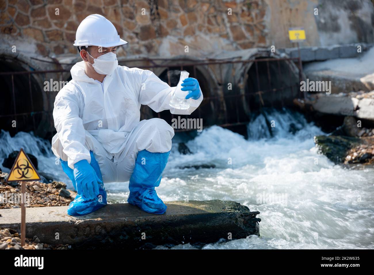 Ecologo che campiona l'acqua dal fiume con vetro per provette e ha fumo bianco Foto Stock