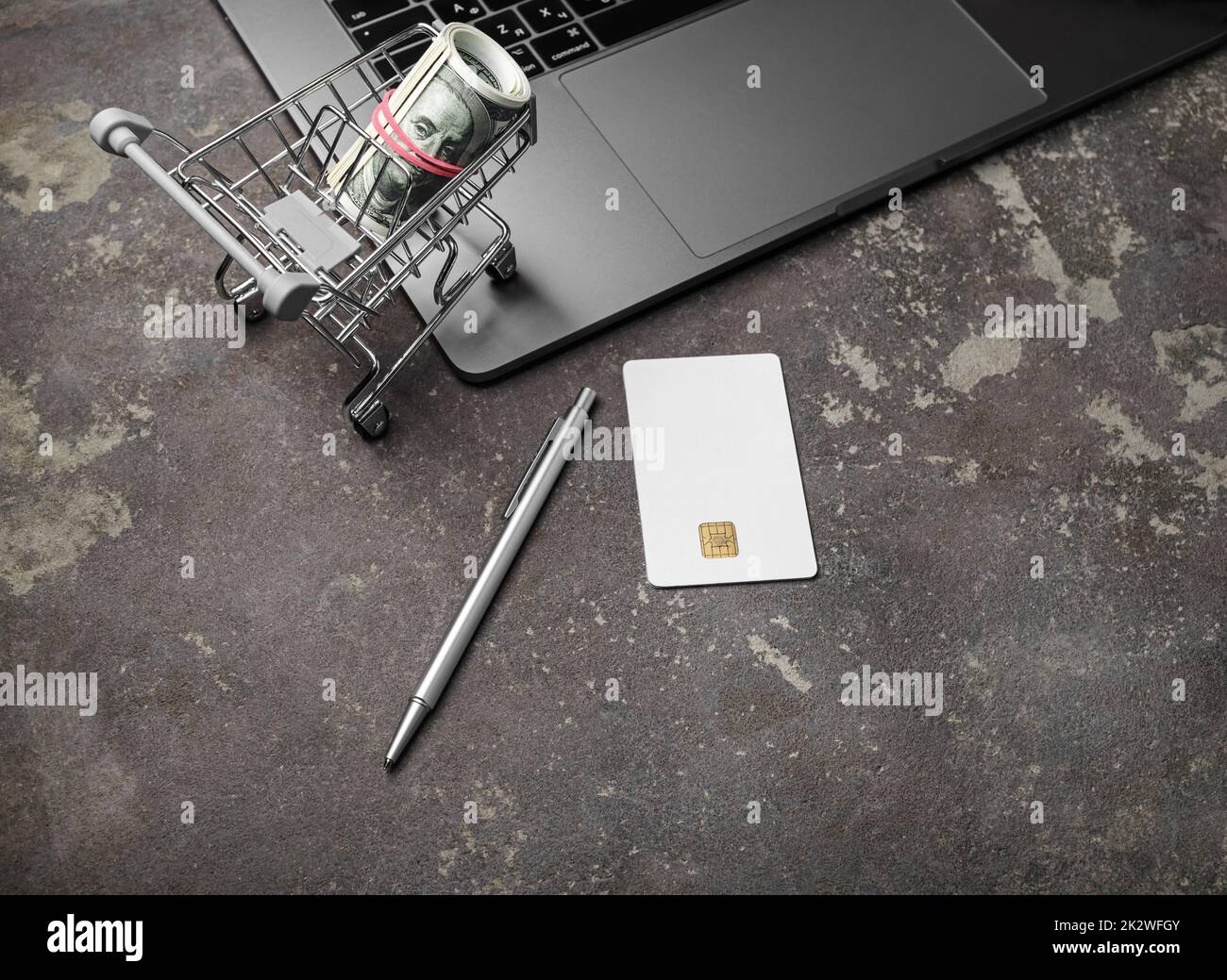 Concetto di shopping online. Computer portatile, carrello con dollari, carta di credito e penna. Foto Stock
