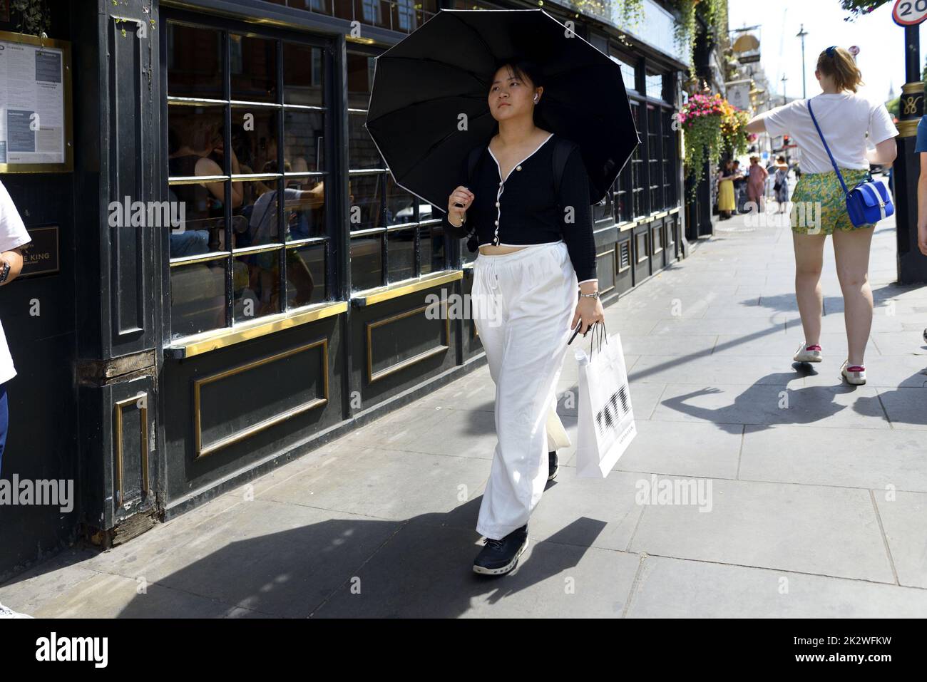 Londra, Inghilterra, Regno Unito. Donna asiatica con unbrella in una calda giornata di sole Foto Stock