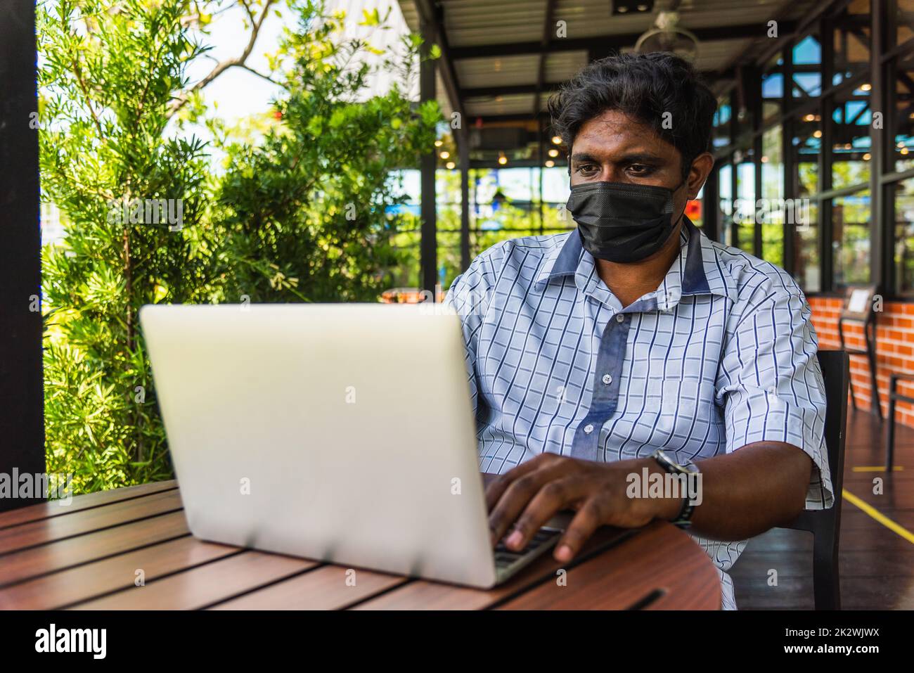 uomo nero seduto al lavoro con un computer portatile Foto Stock