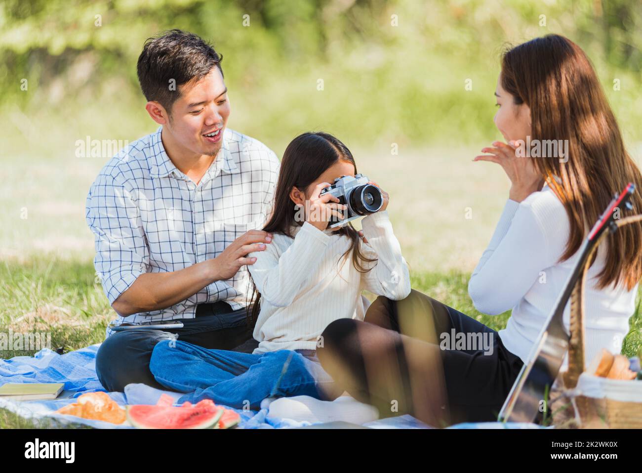 Buona famiglia che si diverte all'aperto insieme seduti sull'erba party con le foto scattate con una fotocamera retrò un picnic Foto Stock