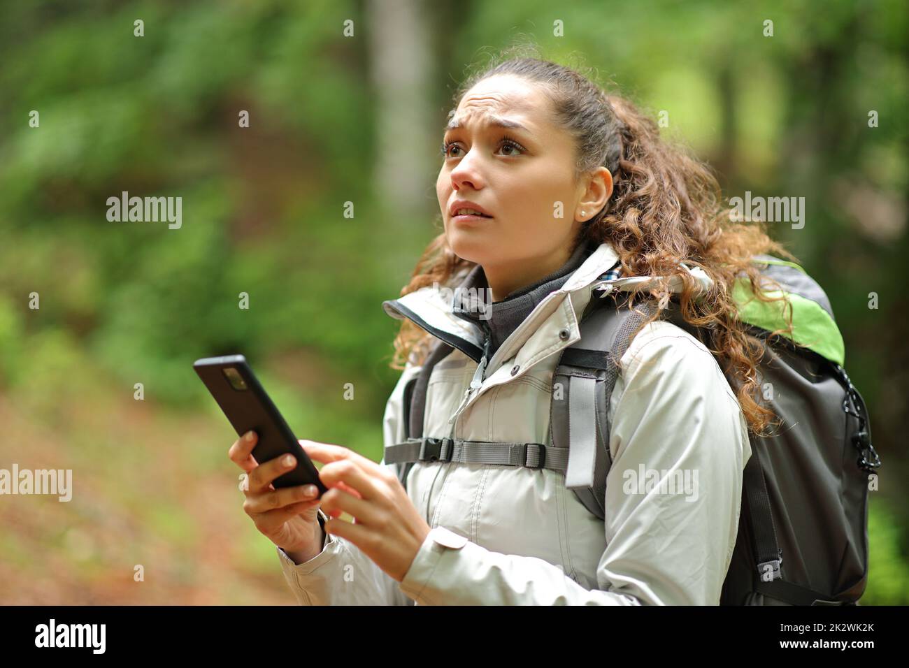 Cercatore perso che cerca la posizione con il telefono in una foresta Foto Stock